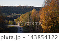 Curving mountain road through autumn forest with golden foliage and distant hills 143854122