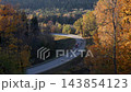 Winding mountain road through colorful autumn forest with truck driving along curve 143854123