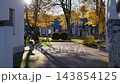 Sunlit residential driveway with autumn trees, long shadows, and blurred neighborhood houses in warm afternoon light 143854125