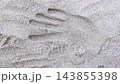 Close-up top view of man hand leaving handprint on white on sand beach. Top-down first person POV of male hand pressing imprint on sandy surface. Summer vacation holiday or memory and identity theme. 143855398