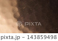 抽象的暗影環在錘紋銅板起伏的表面上平滑地移動。 抽象的暗影環在錘紋銅板起伏的表面上平滑地移動。 143859498