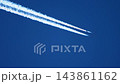 Jet airliner leaving two contrails at cruising altitude in blue sky 143861162