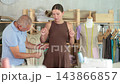 Mature man tailor takes measurements from girl client  143866857