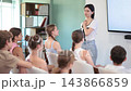 Young woman speaks to audience of teens and preteens listeners  143866859