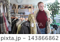 Positive teen girl trying on fur coat during sale in large clothing store  143866862
