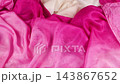 A vibrant red silk fabric falls in slow motion onto a soft cream and light pink textile background. This multi-colored drapery creates elegant layers ideal for luxury fashion and modern apparel design 143867652