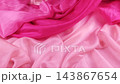 A pink silk fabric falls smoothly onto a magenta textile in slow motion. The elegant soft material creates gentle waves and contrasting colorful folds. 143867654