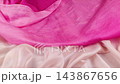 Smooth falling of bright pink and pastel silk fabrics in slow motion. Elegant flowing satin cloth creates beautiful waves for textile industry concepts.  143867656