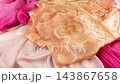 Premium peach silk fabric gently falls onto luxurious orange and pink scarfs in slow motion. This elegant drape showcases the smooth texture of high-quality pastel textiles.  143867658