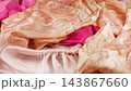Soft fabric with elegant patterns gently flows in slow motion. Peach and pastel pink hues blend perfectly for modern textile designs. Smooth waves create a luxury draped texture ideal for branding.  143867660