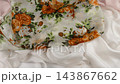Vintage floral silk scarf gently falls onto soft white fabric in slow motion. Organic movement of the textile creates a luxurious backdrop for fashion lifestyle content.  143867662