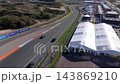 High angle aerial view of race track straight with sports cars orange kerbs pit lane entry event marquees paddock and coastal sand dunes at Circuit Zandvoort in North Holland Netherlands 143869210