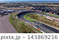 High angle aerial view of race track banked turn sports cars orange kerbs main grandstand pit lane training area campsite sand dunes and North Sea coast at Circuit Zandvoort North Holland Netherlands 143869216