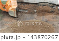 Orange heavy construction equipment working, bucket digging and moving soil on outdoor site, ground level view of large machinery performing earthwork for development project, blurry, copy space 143870267