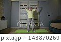 Little girl exercising at home with stick, performing shoulder and back stretches on yoga mat, focused on fitness and physical activity indoors 143870269