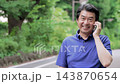 屋外でスマホで通話するシニア男性 143870654