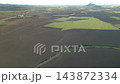 Aerial view of green striped agricultural fields and plowed brown farmland. Drone footage of rural countryside, crop patterns and sustainable farming. High quality 4k footage 143872334