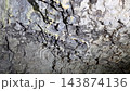 Small forming stalactites with hanging water drops on a rough limestone cave ceiling, geological speleology macro view of stalactite formation in nature. 143874136