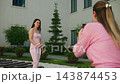 Woman in pink dress stands calmly as another woman takes photos. The photographer smiles, focused on capturing the moment. This footage suits lifestyle, maternity, or fashion themes 143874453