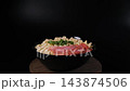 A prepared plate of instant noodles with sausage and parsley turns on a wooden stand against black background. Processed convenience meal concept 143874506