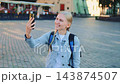 Young woman smiling and taking selfie in urban European square 143874507