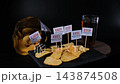 Potato chips rotate on black slate with E160a, E627, E621, E330, E631 and E319 markers beside a drink and open package. Additive risk concept 143874508