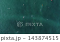 4K top down aerial shot of surfers floating and riding ocean swell waves 143874515