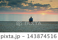 Woman sitting on folding chair admiring sea view on sandy beach daytime 143874516