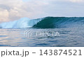Curling turquoise ocean wave breaking with white water foam and spray 143874521