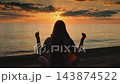 Woman meditating with raised hands on beach at sunset 143874522