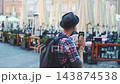 Man using smartphone on outdoor urban pedestrian street with cafe seating 143874538