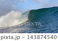 Cinematic shot of ocean wave tube curling under blue sky with clouds 143874540