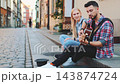 Young couple playing guitar sitting on curb in urban pedestrian street 143874724