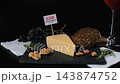 A hand inserts E339, E234, E160b, E452 and E407 labels into fresh cheese surrounded by nuts, herbs, grapes and wine. Food additive awareness concept 143874752