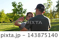 Father and son reunite in sunny park as smiling child embraces dad. Loving family hug shows joy, trust, and connection. Warm summer sunlight creates emotional outdoor memory for family storytelling. 143875140