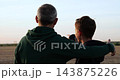 Dad and son point across rural field at sunset. Parent guides child during outdoor talk. Warm golden light shows family connection and trust. Video suggests learning and future planning. 143875226