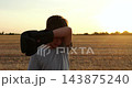 Young boy boxer wipes sweat with boxing gloves in rural field at sunset. He pauses after training and catches his breath. Warm backlight shows fatigue, focus, and emotional reset outdoors. 143875240
