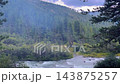 Mountain river flowing through coniferous forest, mist-shrouded valley landscape 143875257