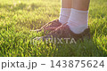 Teen sneakers and white socks stand on green grass in warm sunlight. Close-up footwear scene combines casual youth style, outdoor leisure and summer lifestyle with soft backlight and copy space. 143875624
