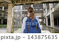 Solo traveler exploring abandoned building courtyard on rainy day 143875635