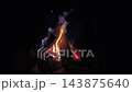 Campfire flames burning brightly at night, sparks rising into darkness 143875640