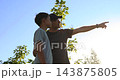 Father and son point toward nature. They explore outdoors in warm sunlight. Family bonding inspires curiosity, learning, and adventure. Boy discovers world with guidance on summer vacation. 143875805