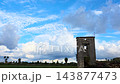 Timelapse of fluffy white clouds gathering and turning into a dark rainstorm cloud over ancient stone tower ruins against blue sky, dramatic nature and architecture footage. 143877473