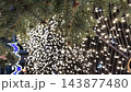 Vertical video. Evergreen branches beneath festive string lights at an outdoor Christmas and New Year display. Winter holiday decor, warm seasonal illumination, New Year celebration background 143877480