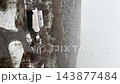 Vertical video. Snowfall over a hillside town and rural road in a vertical elevated view. Winter weather, cold season, residential landscape and rural travel conditions 143877484