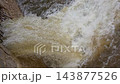 Slow motion close-up of muddy floodwater gushing powerfully through a metal grate into a storm drainage canal during DANA storm aftermath in Spain. 143877526
