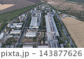 Steelmaking and rolling mill halls beside cultivated farmland in a drone aerial view. Heavy industry, regional development and industrial agricultural land use planning 143877626