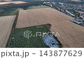 Harvested agricultural fields and orchard in a drone aerial view beside a town. Peri-urban farming, land management and agricultural land use planning 143877629