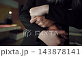 Close-up of man and woman in dark clothes hugging with intertwined hands in dim interior, romantic embrace expressing love, comfort, support and relationship, shallow depth of field 143878141