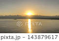 Golden Sun Disappearing Behind a Mountain by the Sea. 143879617